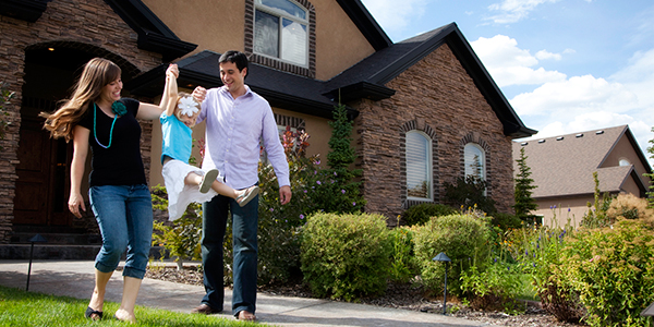 Mother and father swinging their daughter in front of their home